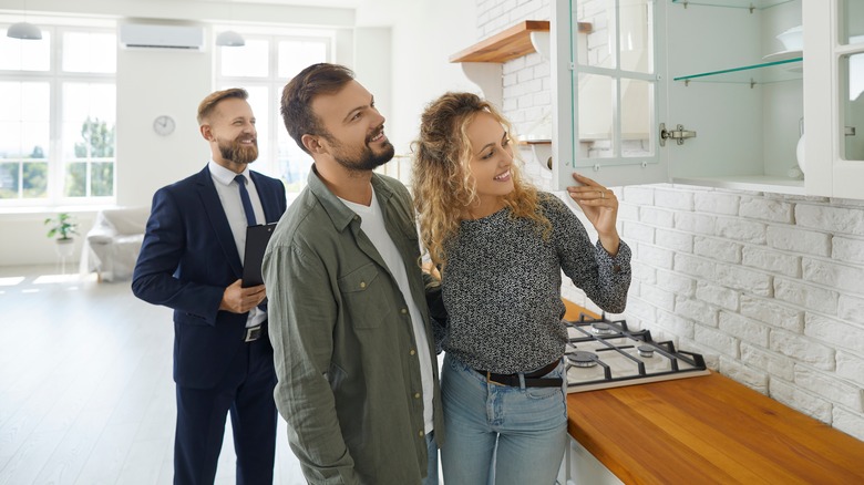 Homebuyers examining kitchen cabinets