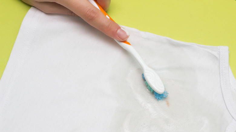 person using toothbrush clean stain