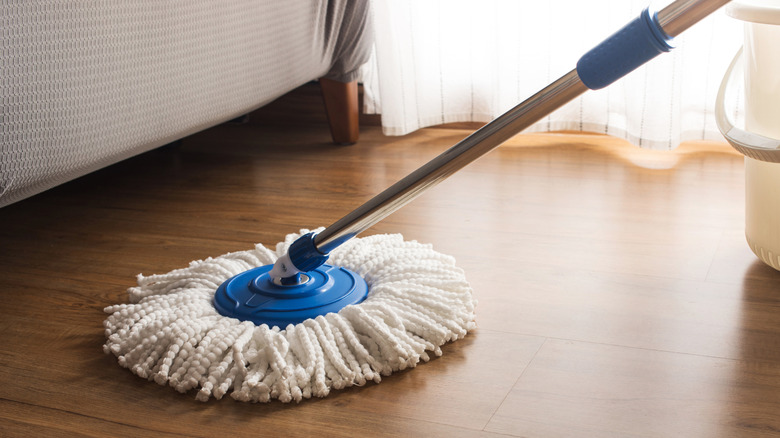 A mop being used to clean a wooden floor