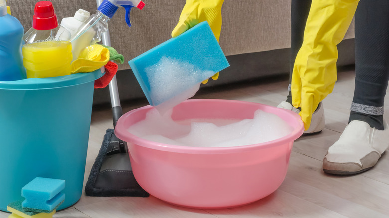 A large blue and smaller red bucket filled with household cleaning supplies