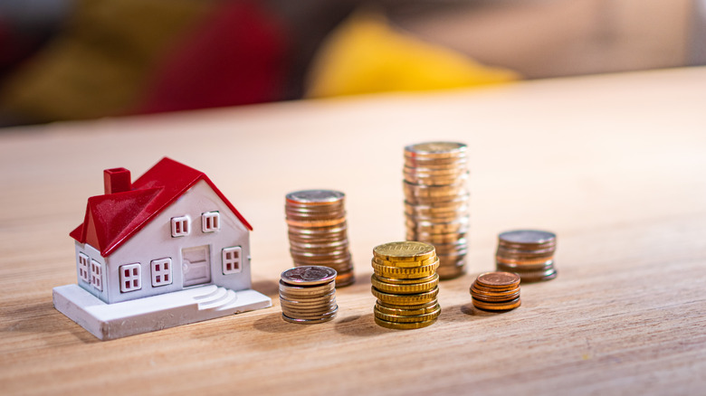 Coins stacked next to miniature house