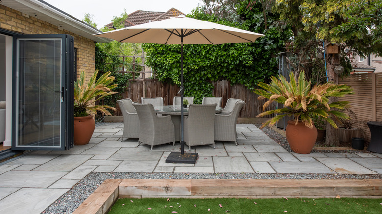 Paver patio with table, chairs, and umbrella outside house