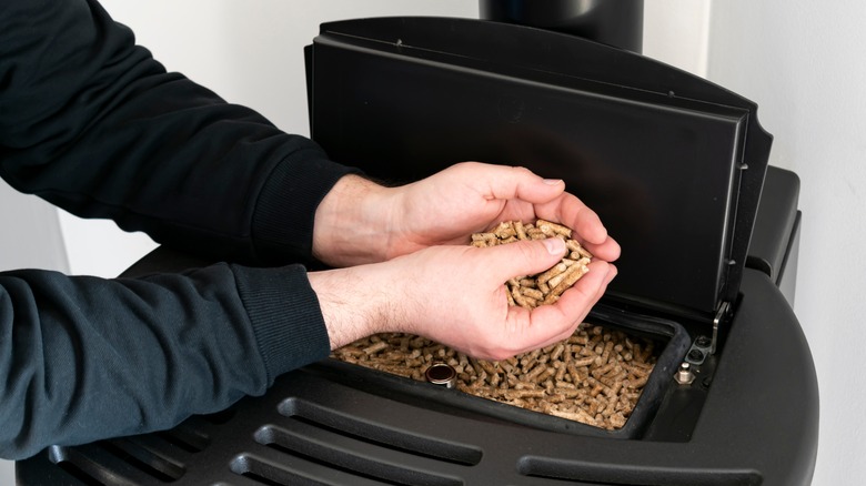 Man loads pellets into stove