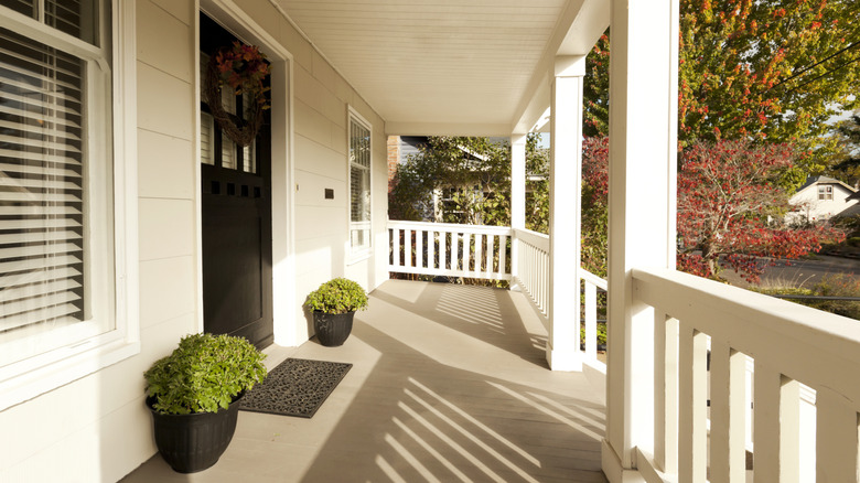 Covered front porch on home with white railing and plants