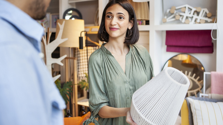 woman holding white lamp in a store