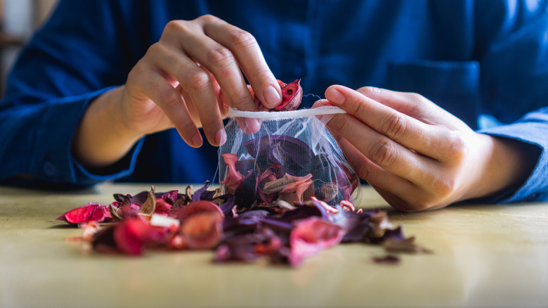 Person's hands placing potpourri in mesh bag