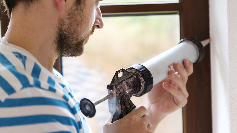 Man caulking around a window