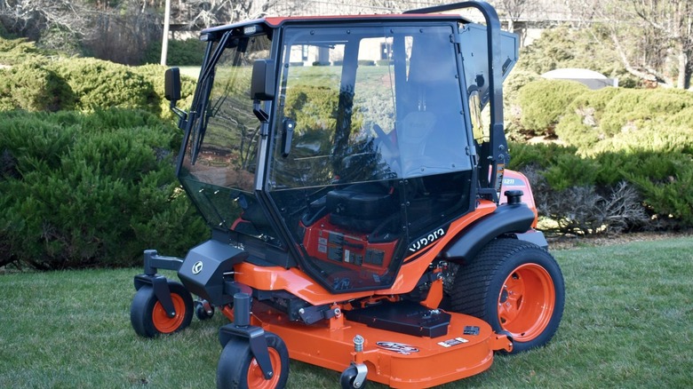 An orange Kubota ride on mower fitted with a Curtis A/C cab