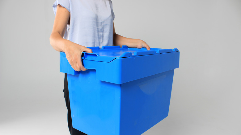 woman carrying plastic bin