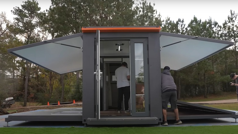 Youtubers setting up gray extendable tiny home