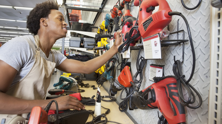 Man looking at power tools hanging from wall