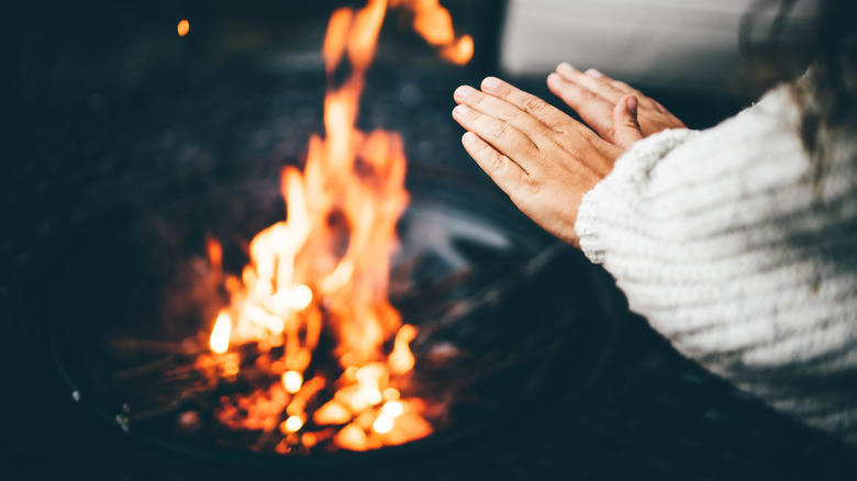 Woman warming hands at campfire