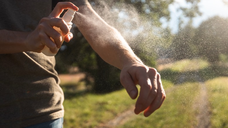 Man spraying arm with repellant