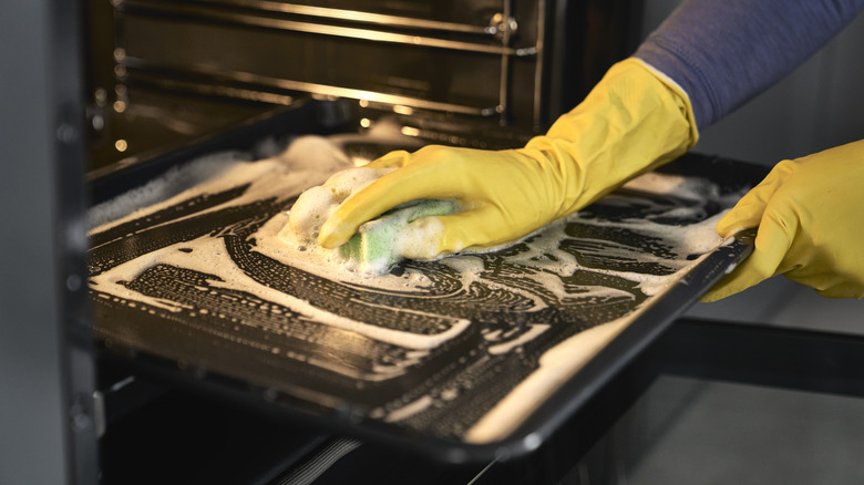 person scrubbing oven door