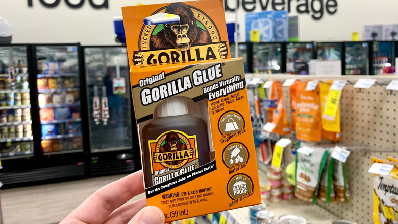 Hand holds a package of Original Gorilla Glue in store aisle