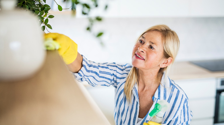 Older woman cleaning floating shelf