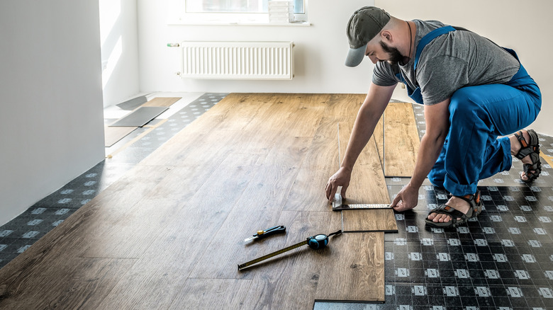 Man installing vinyl plank flooring in a home