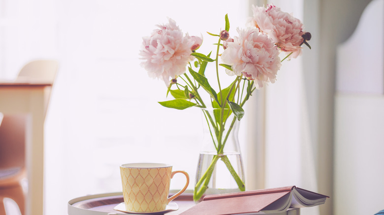 Peonies in glass vase on table