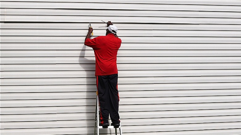 Person repairing vinyl siding