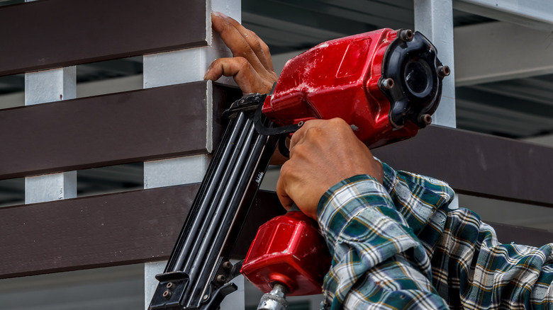 man nailing plank red nail gun