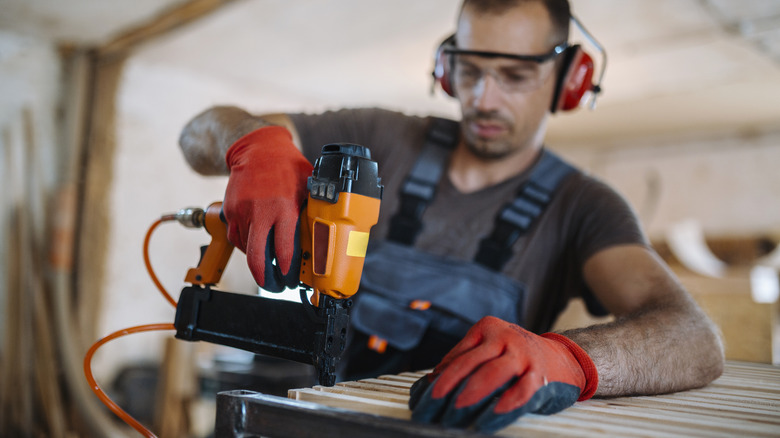 man building table orange nail gun