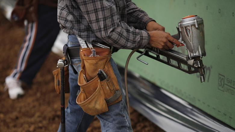 man holding silver nail gun