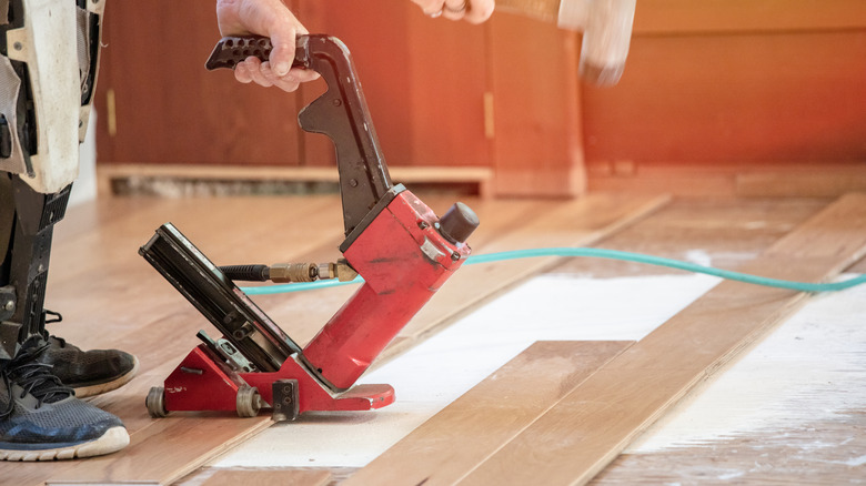 person using red flooring nail gun