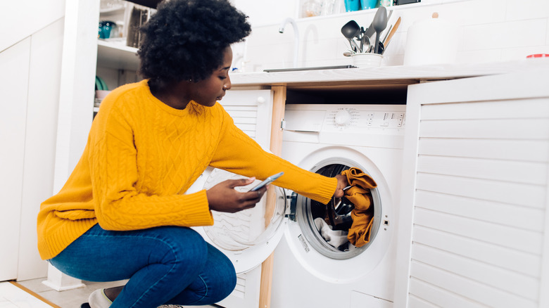 woman using phone with laundry