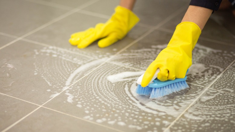 Gloved hands scrubbing floor