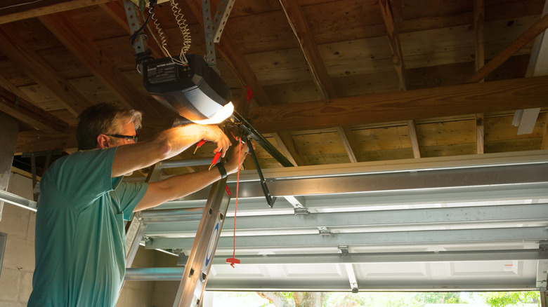 Man on ladder securing garage door emergency release