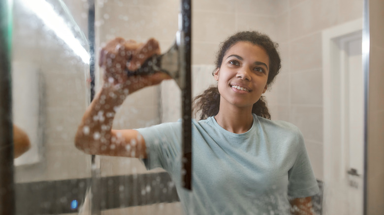 Woman using squeegee on shower 