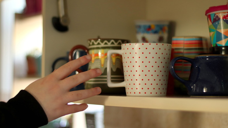 hand reaching for mugs