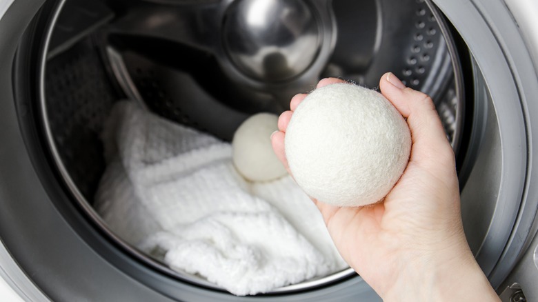 Person putting wool balls in dryer