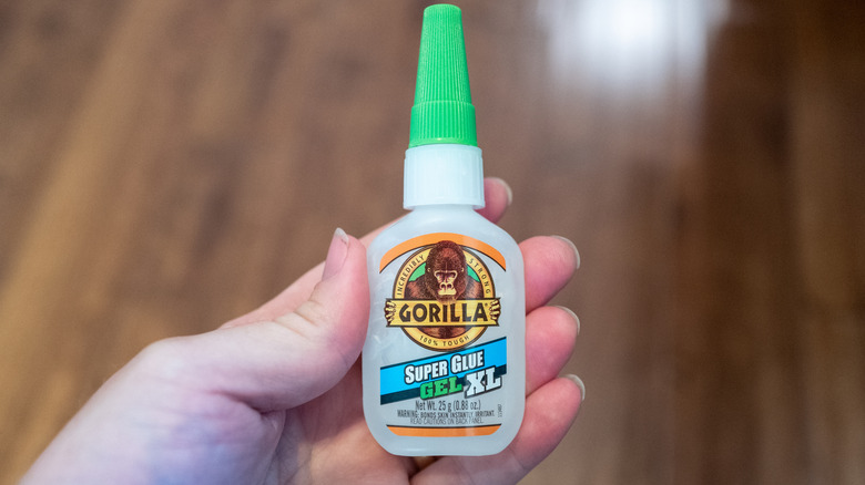 Person holding Gorilla Super Glue bottle.