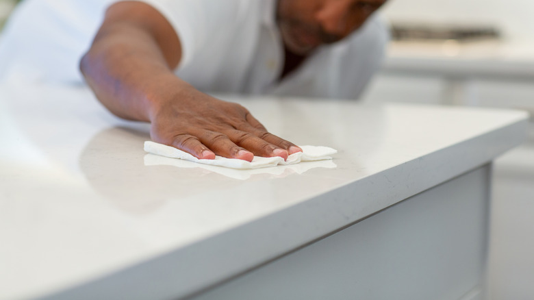 A man uses a wipe to clean a white quartz countertop