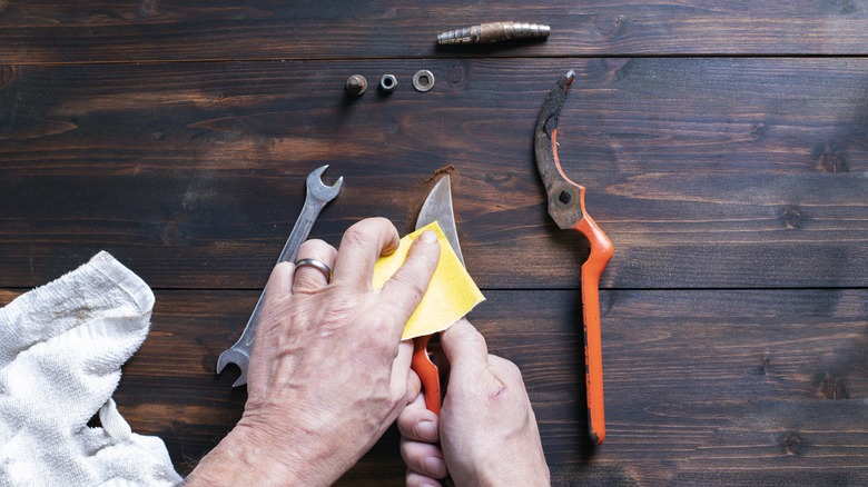 hands sanding rust off pruners